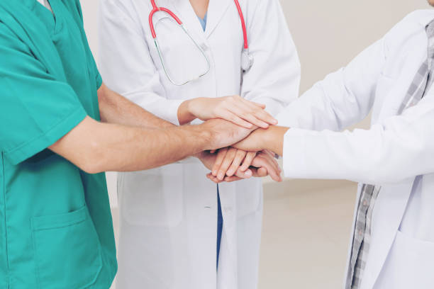 istock Doctor, surgeon and nurse join hands together. 1032949958