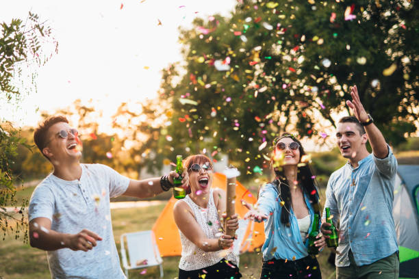 Time for party Small group of friends having fun with confetti at the festival camp music festival camping summer vacations stock pictures, royalty-free photos & images