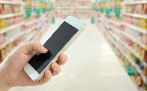 istock woman using mobile phone in supermarket. 1032967792