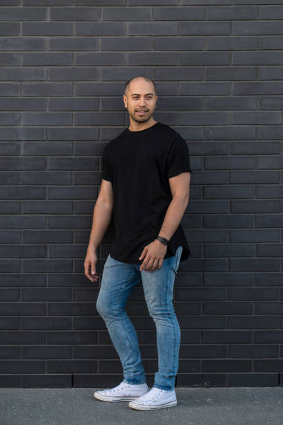 retrato de homem confiante maori/caucasiano de raça mista de casuais jeans e camiseta roupas contra uma parede de tijolo preto na nova zelândia, nova zelândia - minority white simplicity confidence - fotografias e filmes do acervo