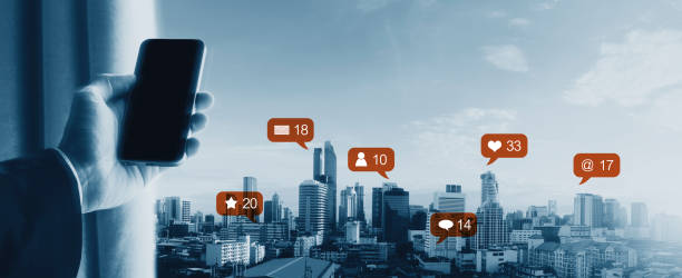 istock Hand using mobile smart phone, with notification icons and city skyline view. Social network, connection and e-commerce business 1033018364