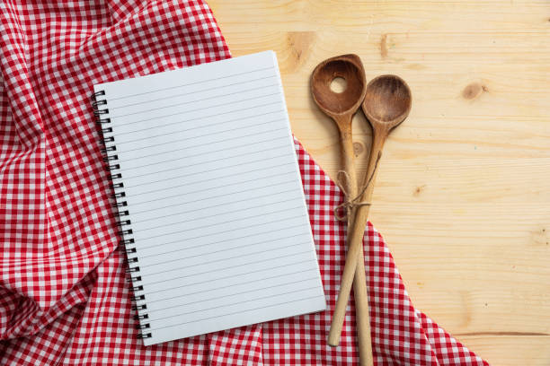 istock Notebook, kitchen utensils and red tablecloth on wooden table, top view, copy space 1033034678