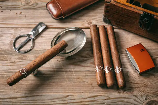 Cuban cigars and smoking accessories on wooden background, top view