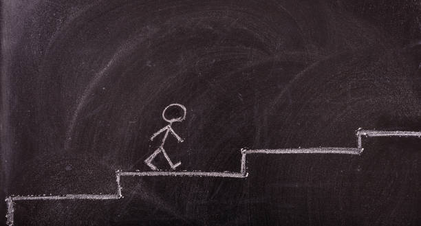 istock Stick man going up the ladder drawing, isolated, on a blackboard. 1033037250