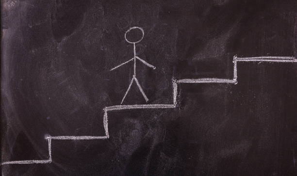 istock Stick man going up the ladder drawing, isolated, on a blackboard. 1033037258