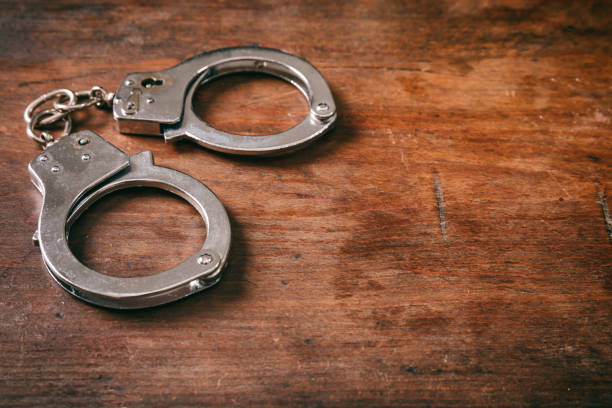 istock Handcuffs isolated and copy space on a wooden background. 1033037300
