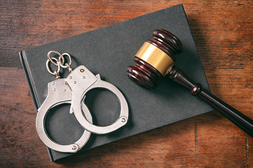 Law and order concept. Handcuffs, gavel on book on a wooden background, top view