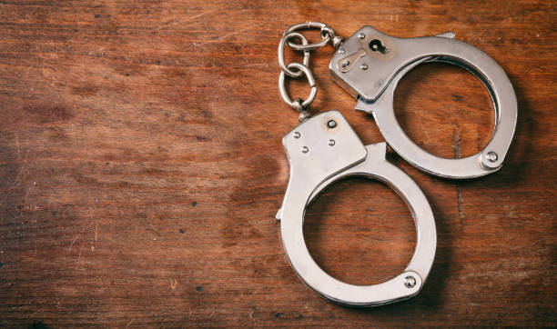 istock Handcuffs isolated and copy space on a wooden background. 1033037304
