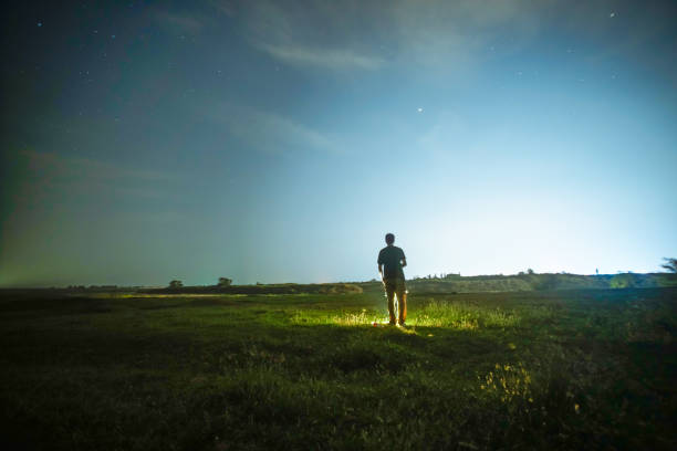 one man standing in the grass field under sky at night