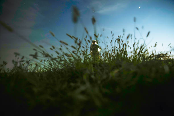 istock one man standing in the grass field under sky at night 1033048430