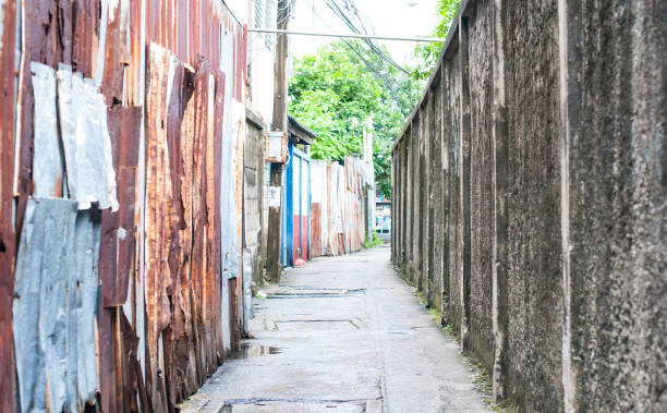 istock Small path into an alley in Bangkok, Thailand, left side is rusty galvanized iron and right side is old cement wall 1033048692
