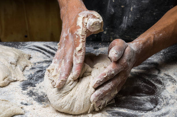 istock Male hands kneading dough on sprinkled 1033052448