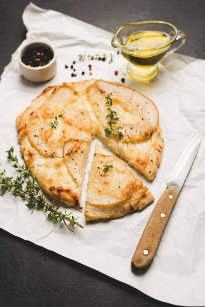 istock Cheese pizza with pear on parchment paper 1033058246