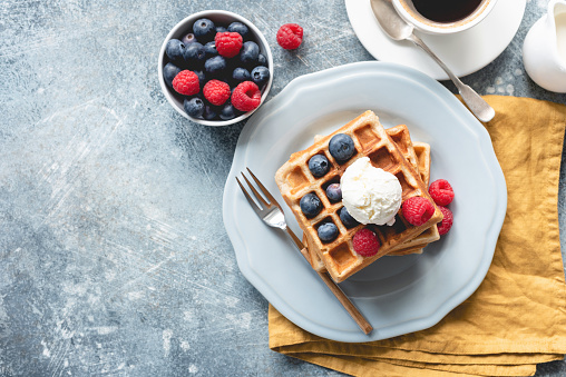 Belgian waffles with ice cream and berries on concrete background. Top view of sweet tasty breakfast. Copy space for your text