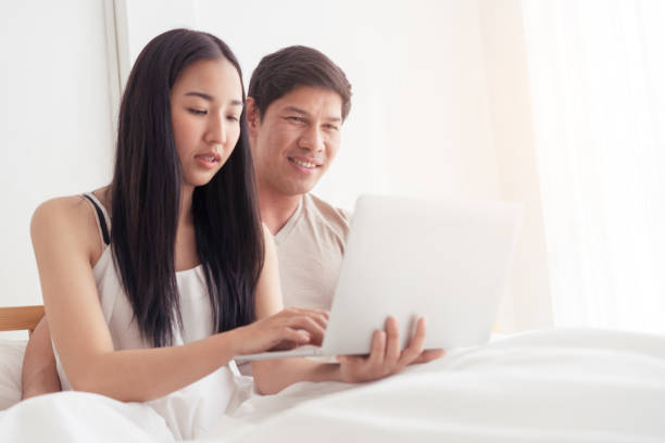 istock Asian couple on bed is using laptop together 1033065834