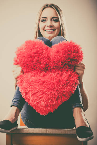 istock woman holding heart shaped pillow love symbol 1033084976