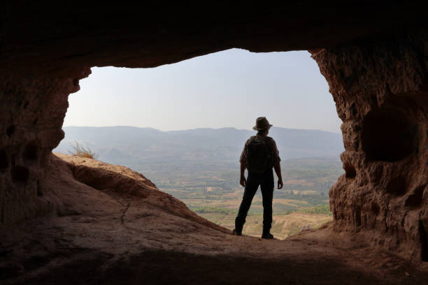 istock ADVENTURER WITH BACKPACK OBSERVING THE VALLEY FROM A CAVE 1033141460