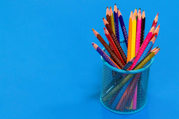 istock Colored pencils in a pencil case on blue background with copy space 1033142696