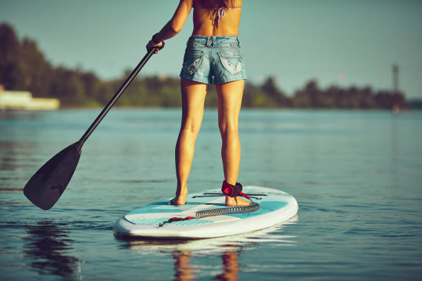 SUP Stand up Surf girl with paddle at sunset SUP Stand up Surf girl with paddle in a blue ocean sea paddleboard surfing oar water sport stock pictures, royalty-free photos & images