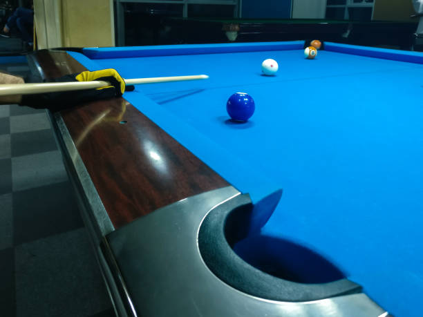 istock Playing billiard - A shot of a man playing billiard on a blue pool table 1033145968