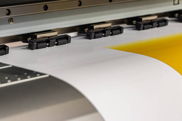 istock Big professional printer, processing a massive roll of glossy paper for a large scale billboard project. Deep saturated yellow ink and motion blur from the printing head. 1033149516