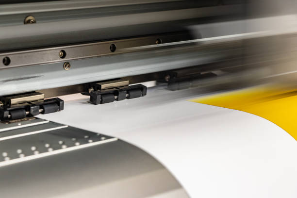 istock Big professional printer, processing a massive roll of glossy paper for a large scale billboard project. Deep saturated yellow ink and motion blur from the printing head. 1033149676