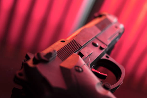 istock Pistol automatic handgun weapon in silhouette in hand of killer atmospheric dark dramatic photo. 1033149928