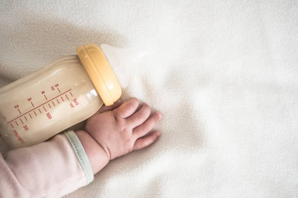 Baby hand and Bottle of Mother breast milk on white blanket background for text space mom and baby food concept babyhood photos stock pictures, royalty-free photos & images