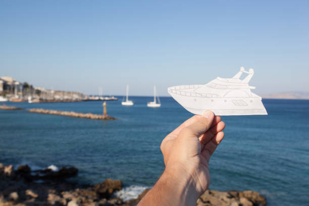 dream to have a yacht. hand holding a paper boat on the sea - recreational boat small nautical vessel sea imagens e fotografias de stock