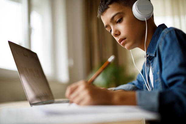 teenage-junge hören musik während der hausaufgaben - mittelschule bücher stock-fotos und bilder