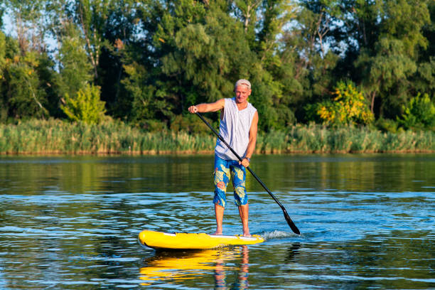 istock Strong man is training on a SUP board on large river 1033167336