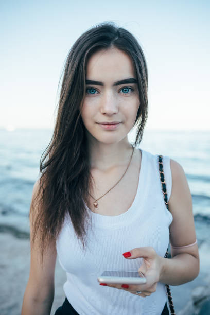 istock Happy young woman holding mobile phone looking at camera 1033177392