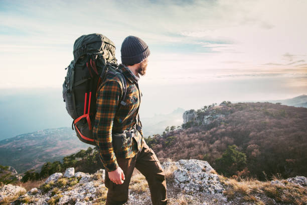 Man traveling with backpack hiking in mountains Travel Lifestyle success concept adventure active vacations outdoor mountaineering sport plaid shirt hipster clothing stock photo