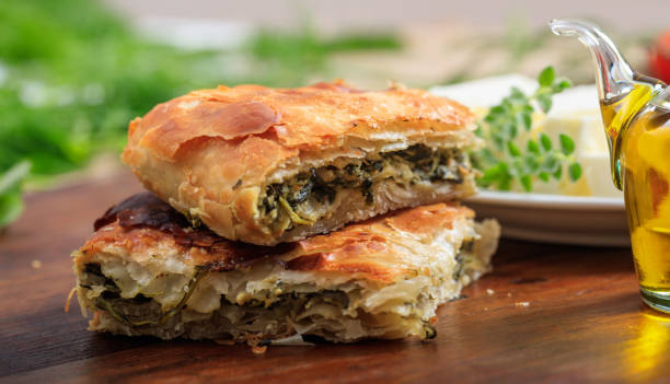 кусочки шпинатного пирога на столе - pie spinach spanakopita filo pastry стоковые фото и изображения