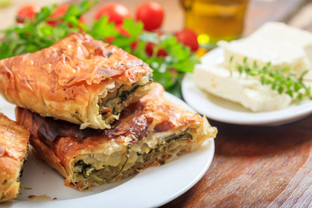 кусочки шпинатного пирога на столе - pie spinach spanakopita filo pastry стоковые фото и изображения