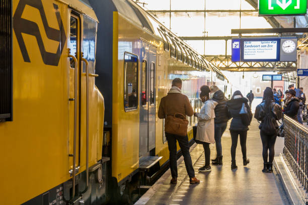 commuters waiting to board train Amsterdam, the Netherlands - November 8, 2016: passengers waiting to board train at Amsterdam central station tasrail stock pictures, royalty-free photos & images