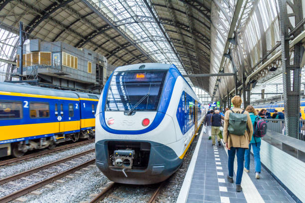 boarding a train at Amsterdam central station Amsterdam, the Netherlands - August 08, 2016: passengers boarding a train tasrail stock pictures, royalty-free photos & images