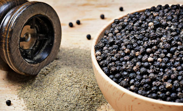 Close up shot of black pepper Black peppercorns and milled pepper, arrangement in a wooden bowl. Close up shot of black pepper, cooking ingredient scene and wooden table. Top view. black peppercorn photos stock pictures, royalty-free photos & images