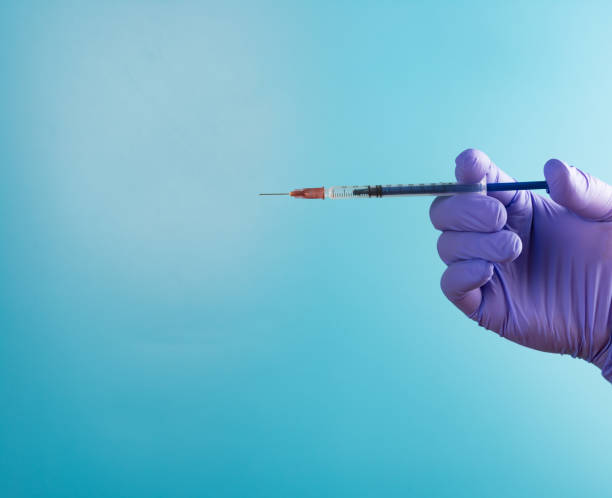 istock hand holding syringe medical injection on blue background 1033219936