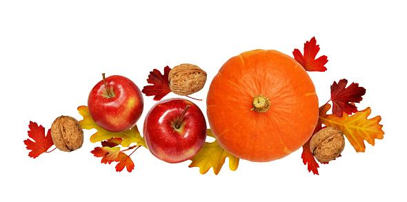 Round pumpkin, apples and walnuts with autumn leaves isolated on white background. Top view. Flat lay.