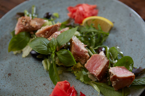 hermosa comida: atún filete en close-up en la ensalada en un plato sobre la mesa, limón y sésamo. - tuna seared tuna steak prepared ahi fotografías e imágenes de stock