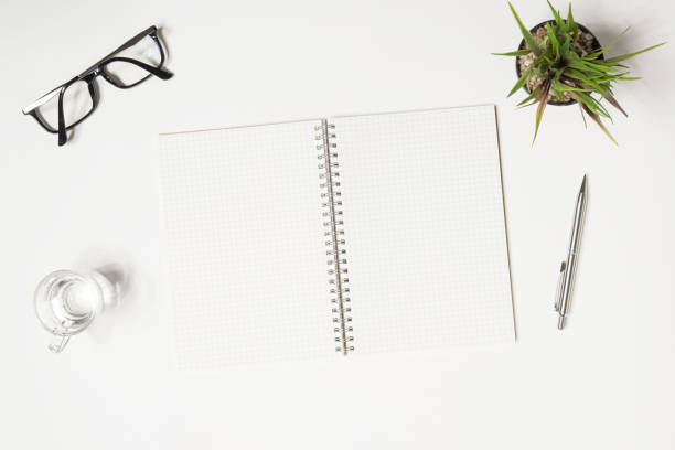 istock Blank notebook with grid lines is on top of white office desk. Top view, flat lay. 1033250218