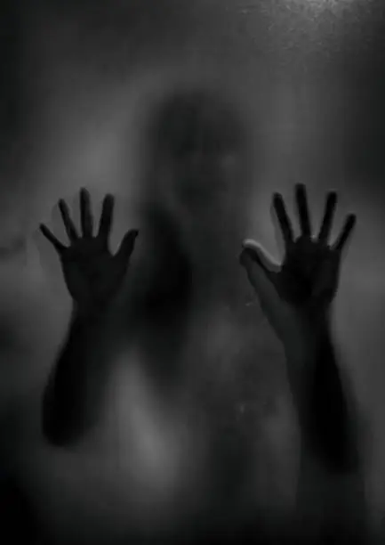 Photo of Horror ghost girl behind the matte glass in black and white. Halloween festival concept.