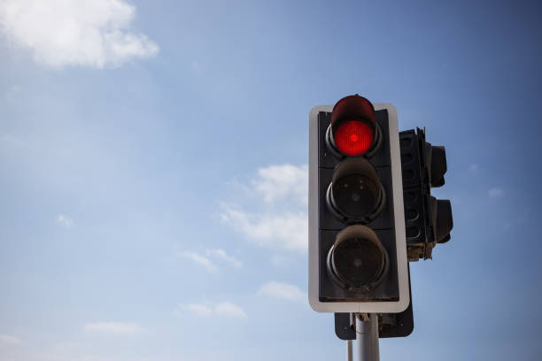 istock Red traffic light. Blue sky with few clouds background. Close up under view, copyspace. 1033275222