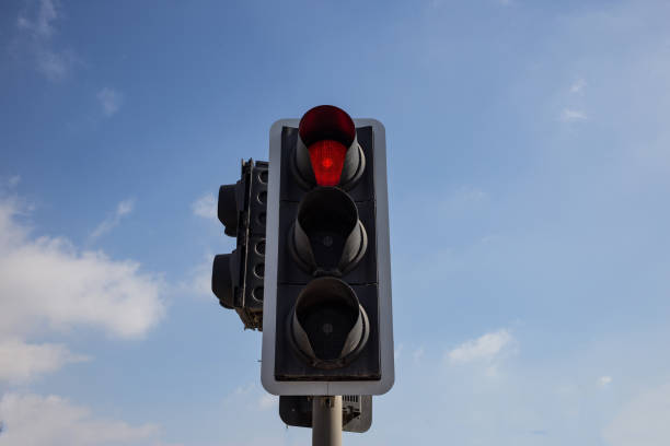 istock Red traffic light isolated. Blue sky with few clouds background. Close up under view. 1033275224