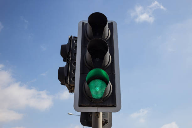 istock Green traffic light isolated.  Blue sky with few clouds background. Close up under view. 1033275234