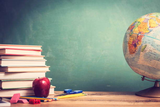 красное яблоко, школьные принадлежности на деревянном столе с глобусом, доска. - textbook book apple school supplies стоковые фото и изображения