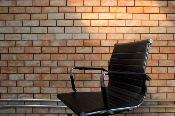 black leather office chair in front of brick wall