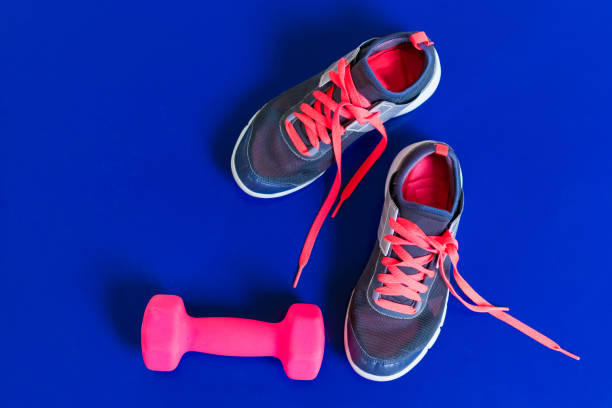 istock gray sneakers pink laces dumbbell on a blue background 1033287884