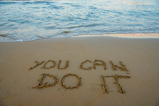 You can do it. Motivational inspirational message concept written on the sand of beach